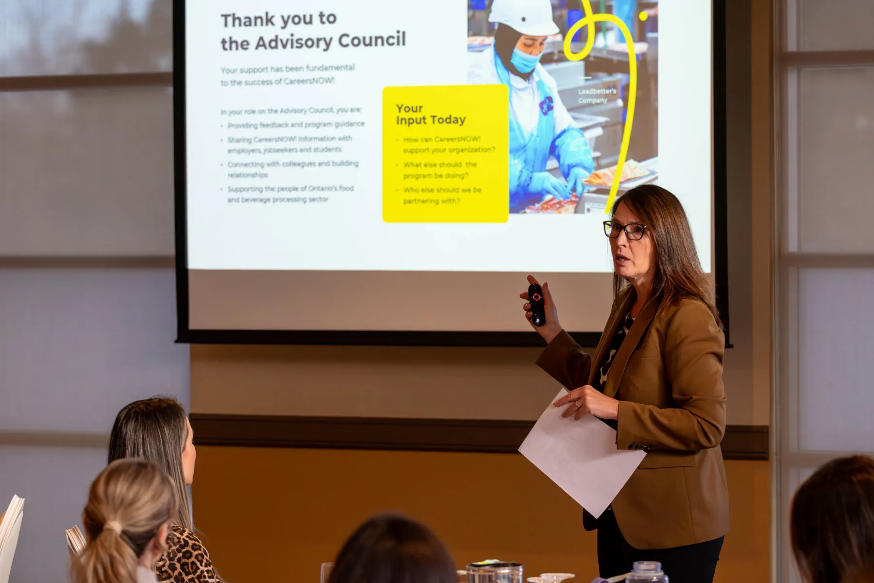 Woman presenting infront of a large projector screen.